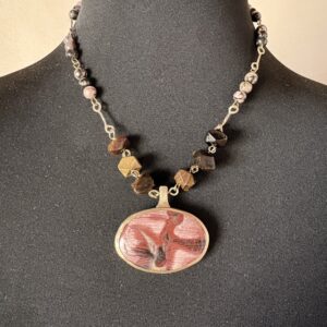 Tour de cou avec pendentif ovale serti clos en jaspe polychrome monté sur une chaine de perles oeil de tigre facetées et de rhodonite rondes, barettes forgées main